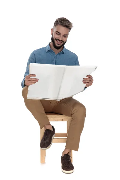 Joven sentado leyendo buenas noticias en el periódico — Foto de Stock