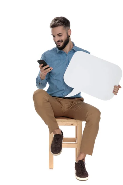 Oturmuş moda adam telefonunda bir sms okur — Stok fotoğraf