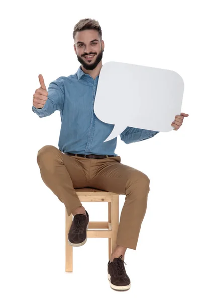 Sentado hombre de negocios mostrando buen gesto mientras sostiene el signo de conversación — Foto de Stock