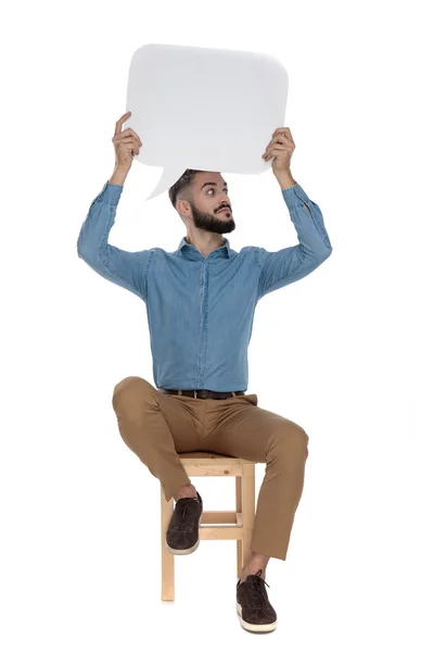 Nieuwsgierige man zitten met een lege boodschap aanmelden — Stockfoto