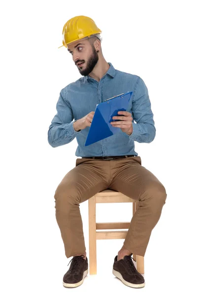 Seated construction student with yellow safety helmet presenting — Stock Photo, Image