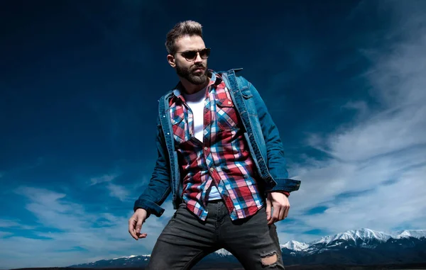 Dramatischer Mann in Jeans und Sonnenbrille posiert draußen — Stockfoto