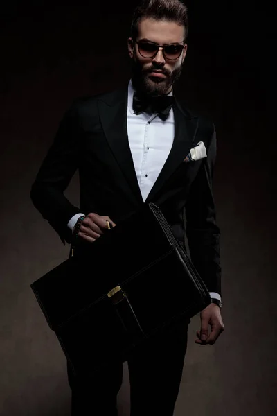 Cool young man in tuxedo  holding briefcase and walking — Stock Photo, Image