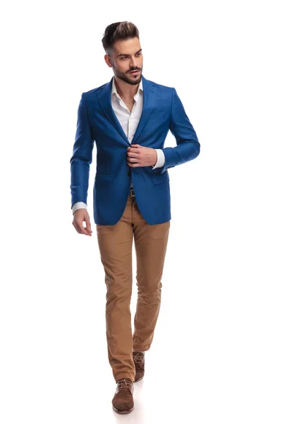 Atractivo hombre de traje abotonando su chaqueta de salón mientras camina — Foto de Stock