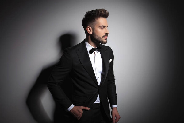 elegant man in black tuxedo standing with hands in pockets