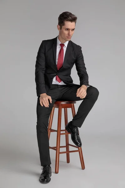 Siedzący sukces człowiek patrząc z dala z rąk na kolana — Zdjęcie stockowe