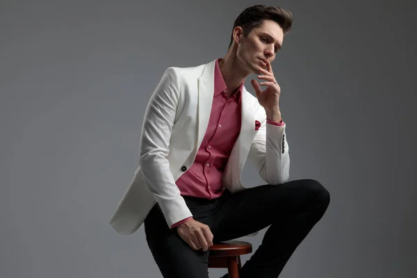 Dudaklarında parmakları ile düşünme takım elbise yakışıklı erkek oturmuş — Stok fotoğraf