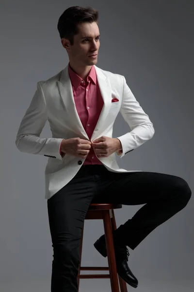 Hombre modelo abotonando su chaqueta de salón mientras mira hacia otro lado — Foto de Stock