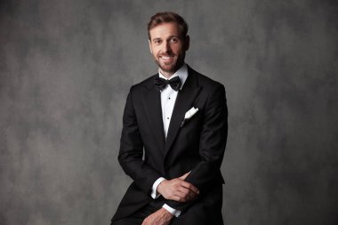 Smokin giyerken kameraya gülümseyen mutlu görünümlü adam