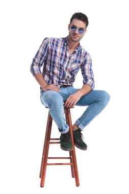 Çekici adam bir taburede oturan ve kollarını dinlenme 