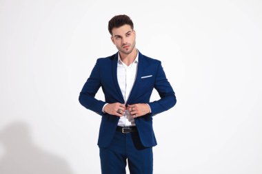 Genç adam yan tarafa bakıyor ve ceketini tamir ediyor.