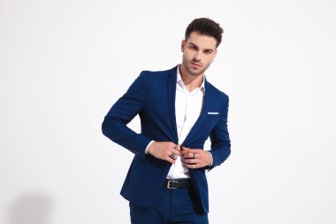 Zarif adam kameraya bakıyor ve ceketini ayarlıyor