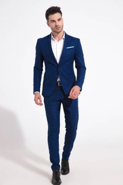 Ciddi görünümlü adam ileri ye doğru yürüyor ve yan bakıyor