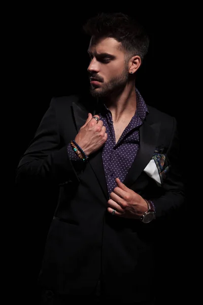 Sensual man looking to the side and adjusting his jacket