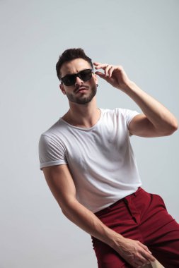 Güneş gözlükünü çıkarmak üzere olan sert adam.