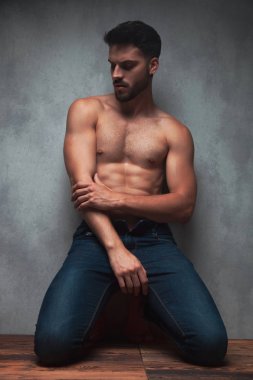 Düşünceli gömleksiz genç adam aşağı bakıyor