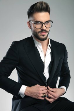 Şaşkın adam yan bakıyor ve ceketinin düğmelerini çözerek