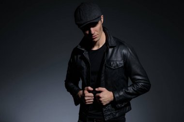 Ciddi görünümlü adam çekme ve onun deri ceket sabitleme 