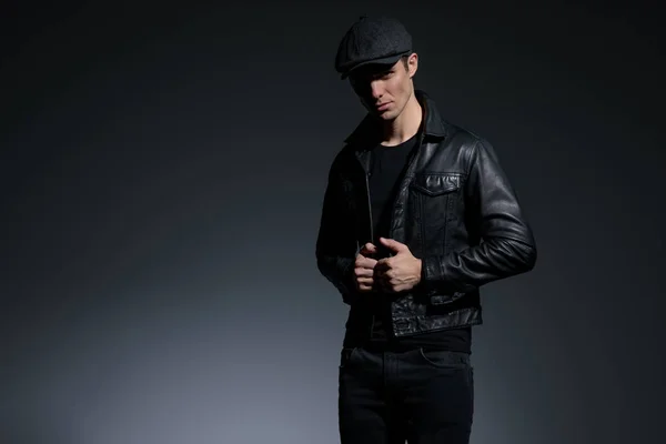 Uomo dall'aspetto serio che regola la sua giacca di pelle nera — Foto Stock