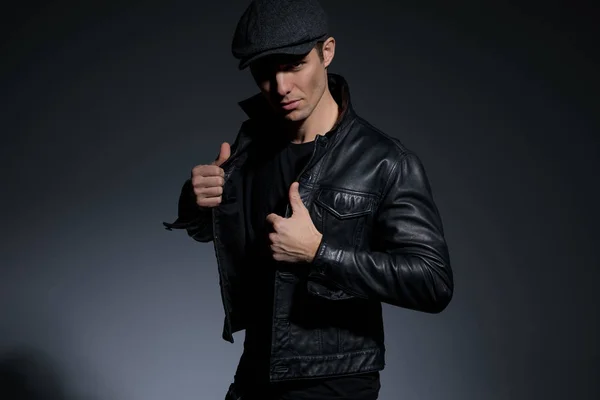 Selbstbewusster junger Mann arrangiert seine schwarze Lederjacke — Stockfoto