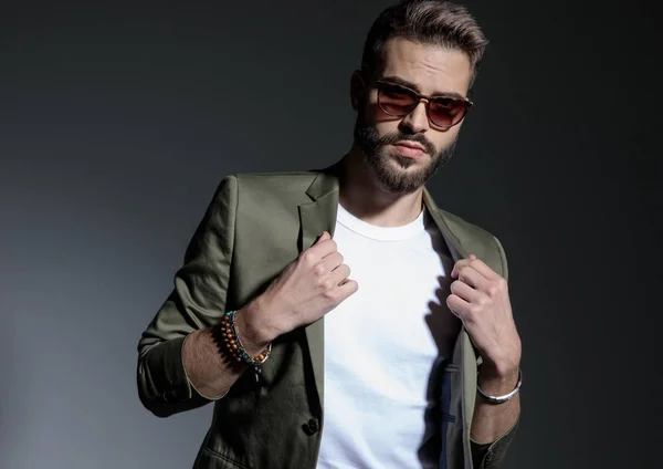 Close up of determined man adjusting his green jacket's collar — Stock Photo, Image