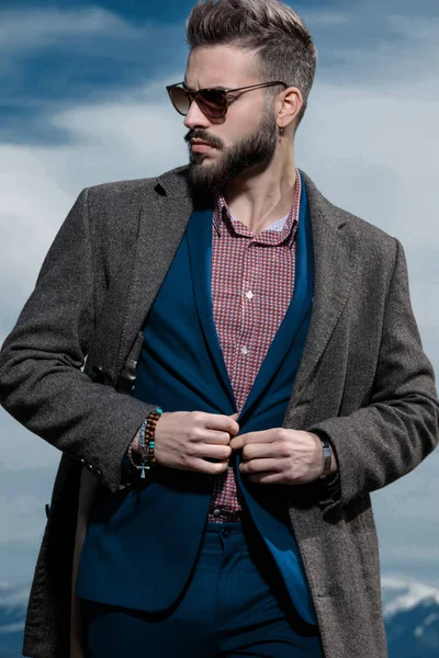 Mystified man adjusting his jacket and curiously looking sideway — Stock Photo, Image