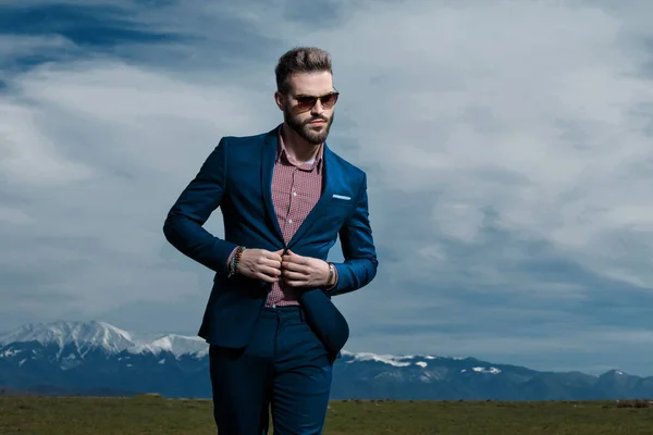Hombre de aspecto serio ajustando su chaqueta y caminando —  Fotos de Stock