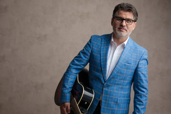 Empresário positivo segurando sua guitarra e sorrindo — Fotografia de Stock