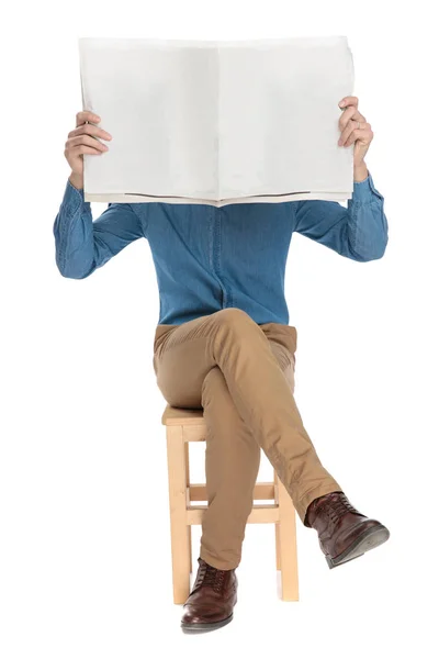 Ung kille som håller en tidning framför sitt ansikte — Stockfoto