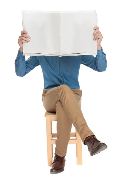 Jovem segurando um jornal na frente de sua cara — Fotografia de Stock