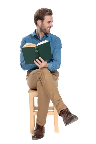 Веселый человек, держащий книгу и смеющийся в сторону — стоковое фото