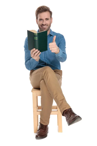 Αισιόδοξος τύπος δίνοντας ένα αντίχειρα και κρατώντας ένα βιβλίο — Φωτογραφία Αρχείου