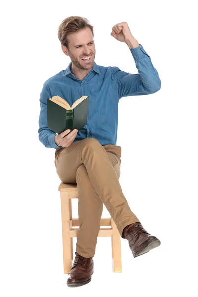 Glücklicher junger Mann hält ein Buch in der Hand und feiert — Stockfoto