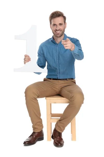 Homem otimista apontando e segurando um número um — Fotografia de Stock