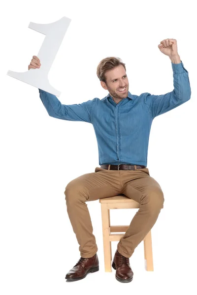 Joyful young man holding a number one and celebrating — Stock Photo, Image