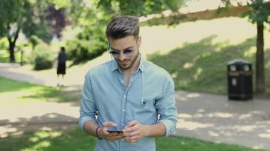 Genç sıradan bir adam yürüyor ve mesajlaşıyor.