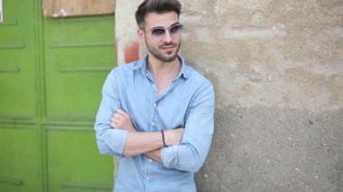 Genç sıradan bir adam eski binaya yaslanıyor.