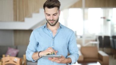 genç rahat adam bir tablet üzerinde çalışmak ve yan görünüyor