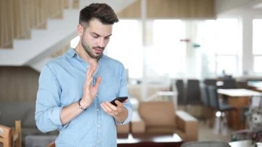 genç rahat satıcı ayakta ve cep telefonu dokunarak ve nihayet heyecanla büyük bir galibiyet kutluyor