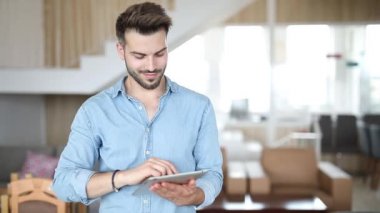 gülümseyen rahat adam bir tablet ped bilgisayarda çalışmak ve göz kırpma ile el işareti kadar ok başparmak yapar