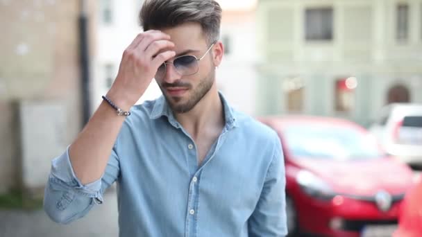 Eski bir şehrin sokaklarında saçlarını elini geçirerek saç stilini sabitleme rahat bir genç adam closeup — Stok video