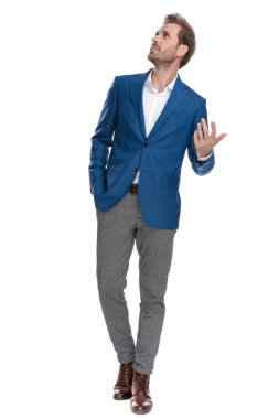 Düşünceli yukarı bakıyor ve elini cebinde tutuyor.