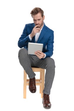 Endişeli rahat adam onun tablet üzerinde okuma