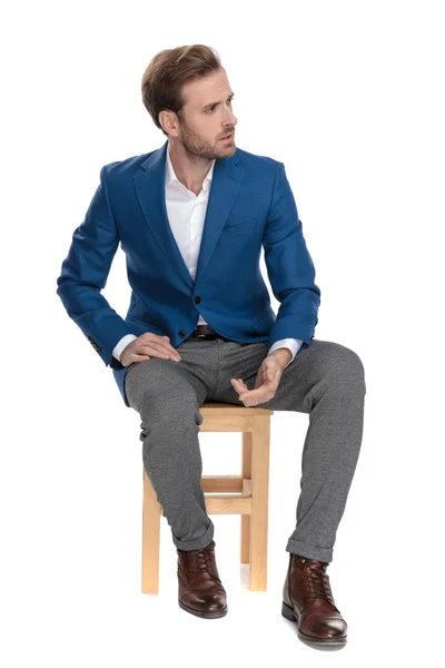 Zdenerwowany casual mężczyzna siedzi i pochylony na nogę — Zdjęcie stockowe