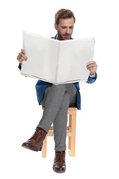 Konzentrierter, lässiger Mann, der im Sitzen eine Zeitung liest — Stockfoto