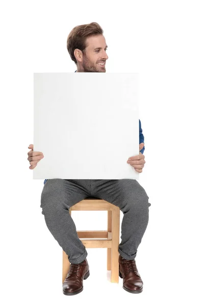 Joven casual sosteniendo una cartelera en blanco — Foto de Stock