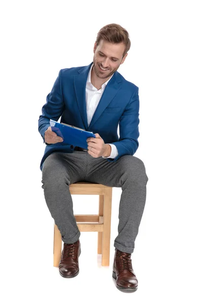 Joyful casual Guy skrattar och läser från en Urklipp — Stockfoto