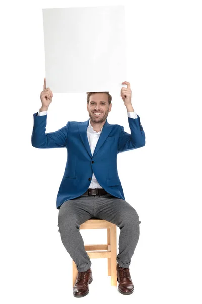 Happy casual man holding an empty billboard above his head — Stock Photo, Image