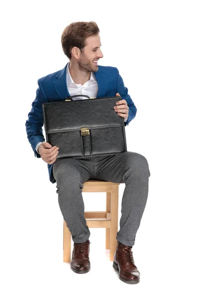 Молодой бизнесмен держит свой портфель и смеется — стоковое фото
