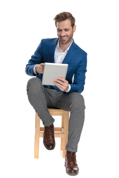 Homem casual alegre lendo em seu tablet e rindo — Fotografia de Stock